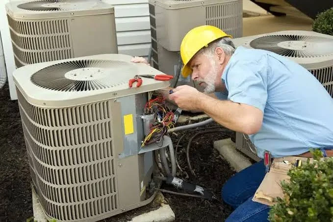 Technician inspecting outdoor cooling equipment with its service panel open